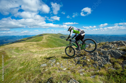 A man with the bicycle is riding down the hill.
