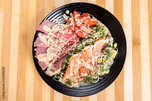 Salmon and tuna sashimi in a salad with herbs.