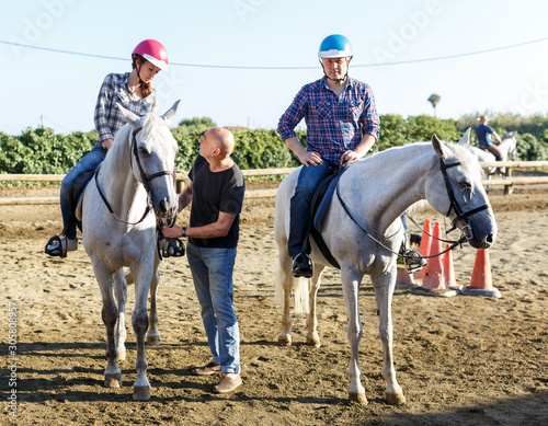 Trainer talking to woman while riding horse at farm