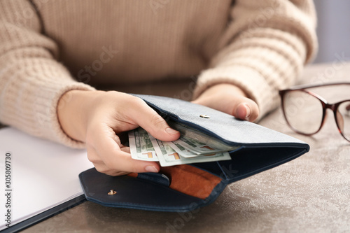 Photos Woman putting money into wallet at brown table, closeup