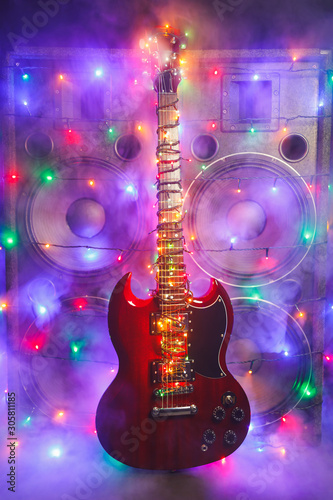 electric guitar with festive Christmas lights and music speakers in smoke