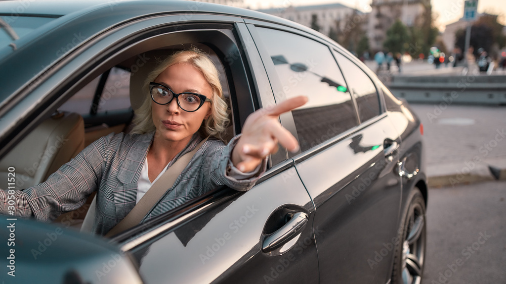 Feeling angry. Portrait of angry business woman gesturing with hands and arguing with somebody while driving a car