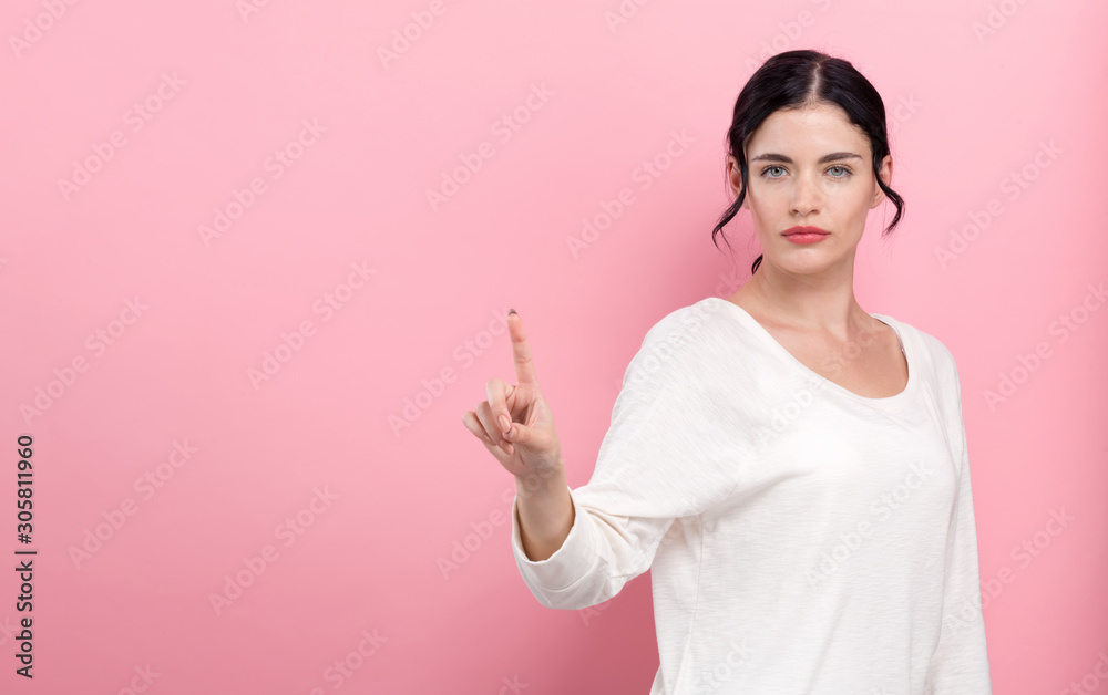 Young woman pointing at something on a pink background Young woman pointing at something on a pink background