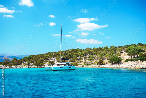 Sailing yacht catamaran boat with white sails on turquoise waters of sea. © IrynaV