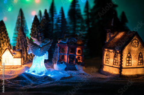 New Year miniature house in the snow at night with fir tree.