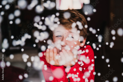 young boy blowing artificial snow flakes at home. Christmas concept