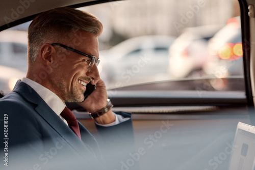 So happy to hear you. Side view of mature businessman sitting in the car and talking by the phone