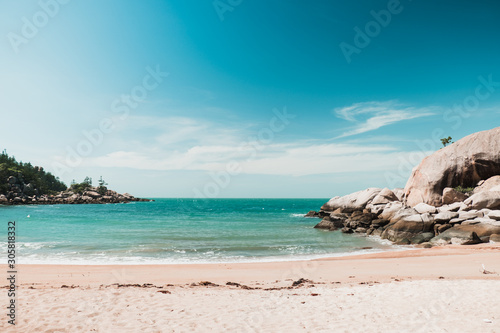 Sunny beach on Magnetic island  Australia with rocks and hills around