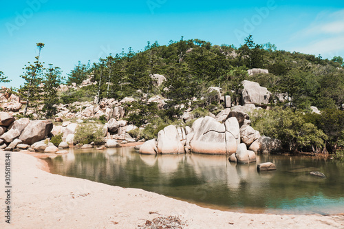 Sunny beach on Magnetic island, Australia with rocks and hills around