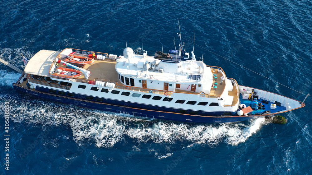 Aerial drone photo of luxury yacht cruising near iconic village of Oia, Santorini island, Cyclades, Greece Aerial drone photo of luxury yacht cruising near iconic village of Oia, Santorini island, Cyclades, Greece