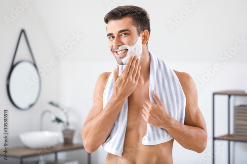 Handsome young man shaving at home photo