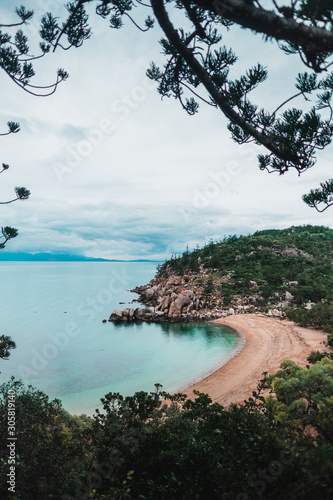 Sunny beach on Magnetic island, Australia with rocks and hills around