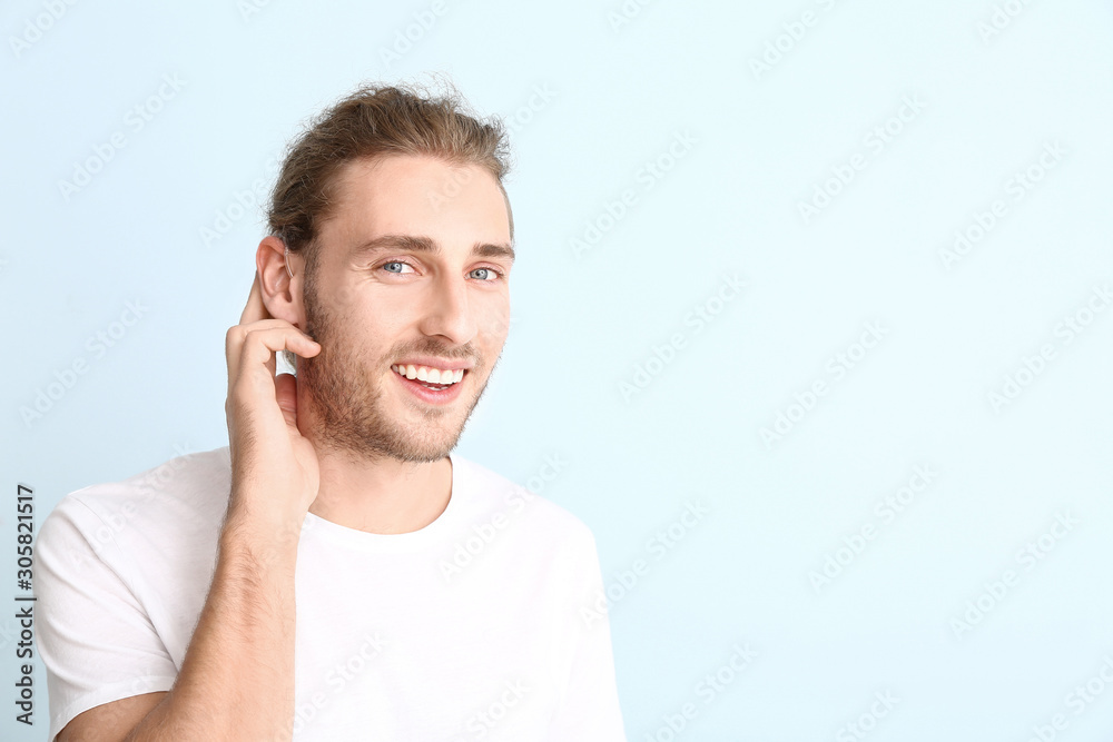Young man with hearing aid on color background Young man with hearing aid on color background