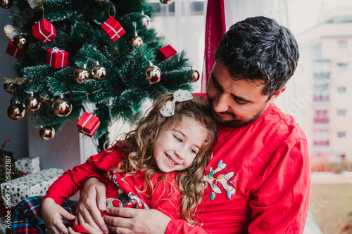 father and daughter at home wearing matching pajamas. christmas season