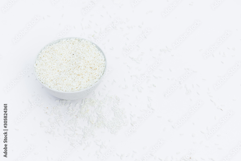 Milled rice in a cup and milled rice spread on a white ground