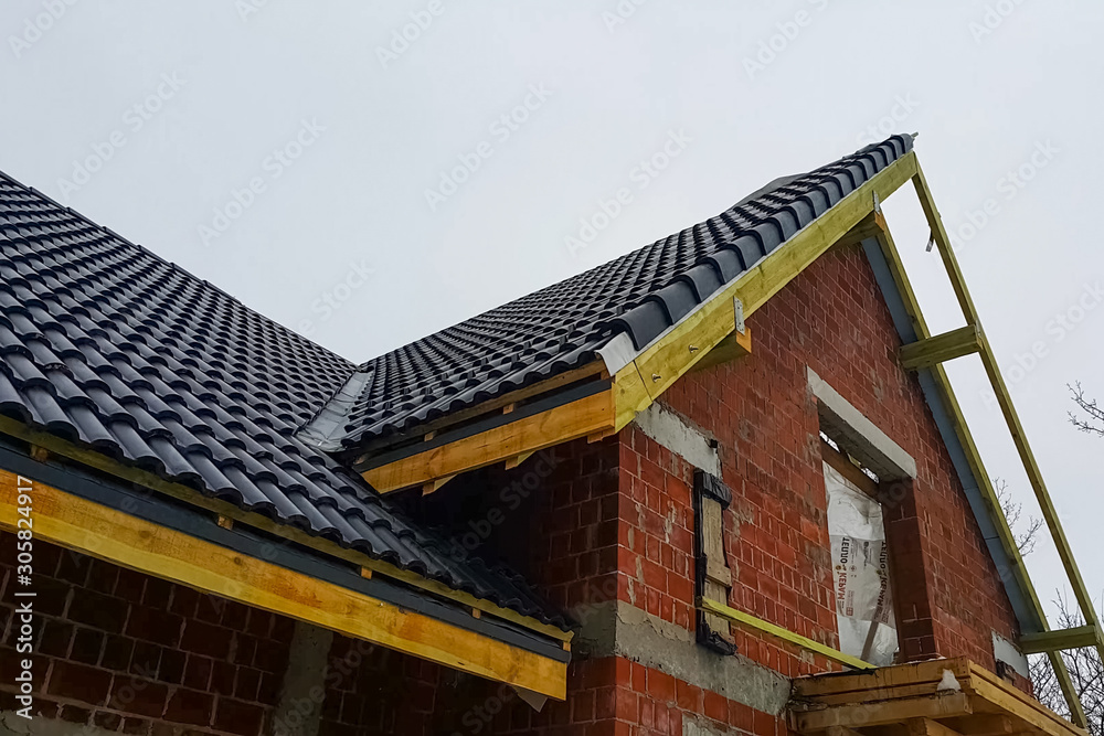 Installation of the roof of the house from ceramic black tiles. Installation of the roof of the house from ceramic black tiles.