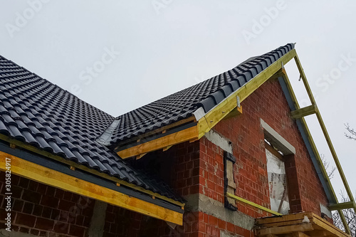 Installation of the roof of the house from ceramic black tiles.