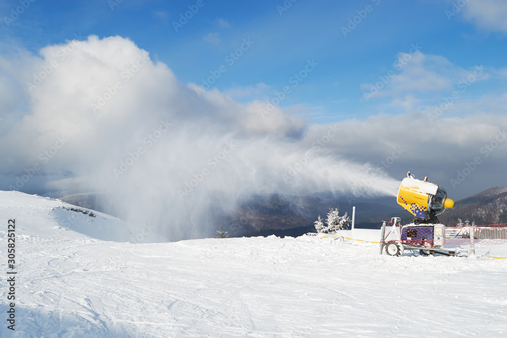 Snow cannon machine blowing artificial snow on Azuga ski domain, Prahova Valley region, Romania, during the Winter low season, due to the lack of natural snow.