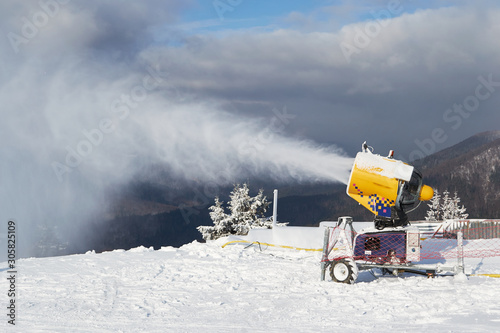 Snow cannon machine at work on a ski piste, at Azuga ski domain, Prahova Valley region, Romania.