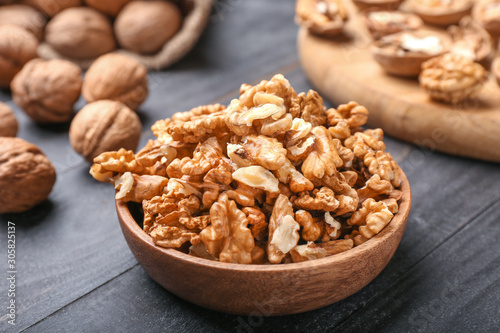 Plate with tasty walnuts on wooden background