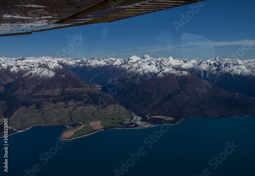 vue aérienne à basse altitude, au-dessus du parc national mount aspiring, en nouvelle zélande, avec un magnifique ciel bleu, et des sommets enneigés © Stan-972