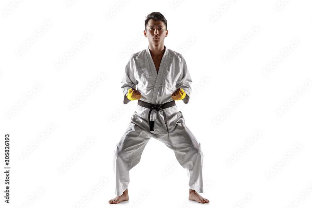 Confident korean man in kimono practicing hand-to-hand combat, martial arts. Young male fighter with black belt training isolated on white studio background. Concept of healthy lifestyle, sport. Confident korean man in kimono practicing hand-to-hand combat, martial arts. Young male fighter with black belt training isolated on white studio background. Concept of healthy lifestyle, sport.