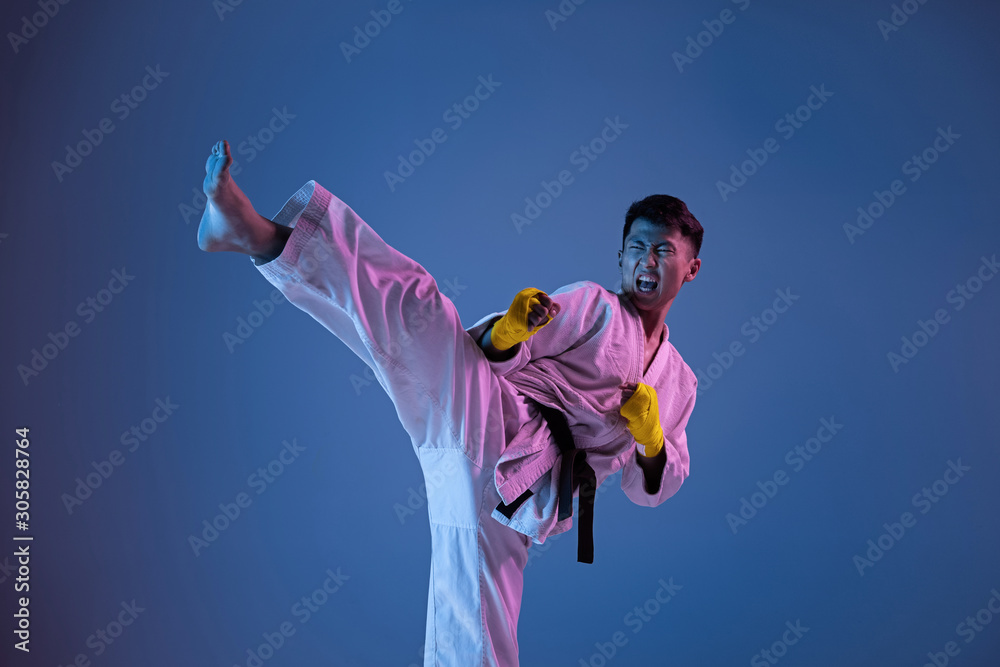 Confident korean man in kimono practicing hand-to-hand combat, martial arts.  Young male fighter with black belt training on gradient background in neon  light. Concept of healthy lifestyle, sport. Stock Photo | Adobe