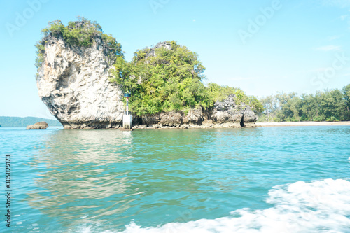 A rocky island in the middle of the sea with trees on an island in Thailand.