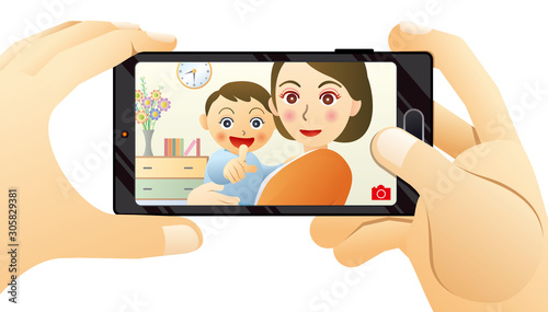 スマートフォンで撮影するパパに向かって笑うママと赤ちゃん