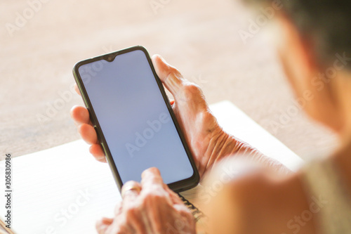 Old woman holding smart phone for shpping online