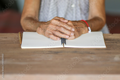 Old woman hands on notebook on wooden table