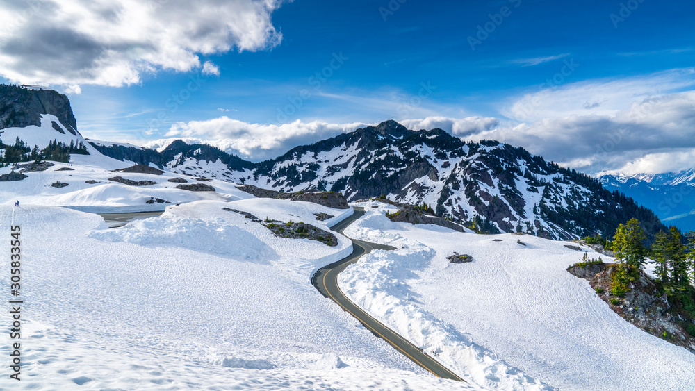 Washington, USA. Uphill road landscape in winter at Mount Baker. Asphalt road with sideways full of snow.