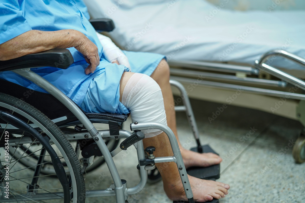 Obraz premium Asian senior or elderly old lady woman patient accident at knee with bandage on wheelchair in nursing hospital ward : healthy strong medical concept..