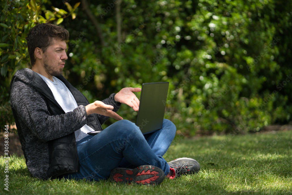 Blond man looking at the screen of his computer and moving his hands like he is complaining. Technological concept. Natural Environment Blond man looking at the screen of his computer and moving his hands like he is complaining. Technological concept. Natural Environment