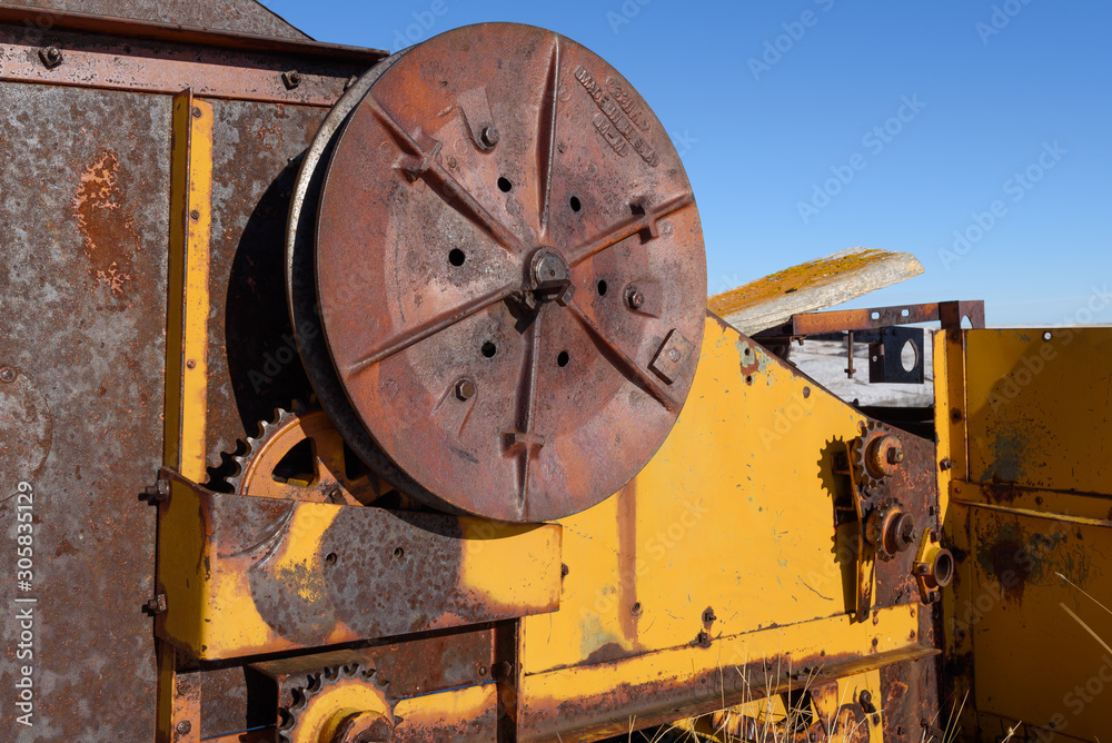 closeup of old yellow combine pulley and gear