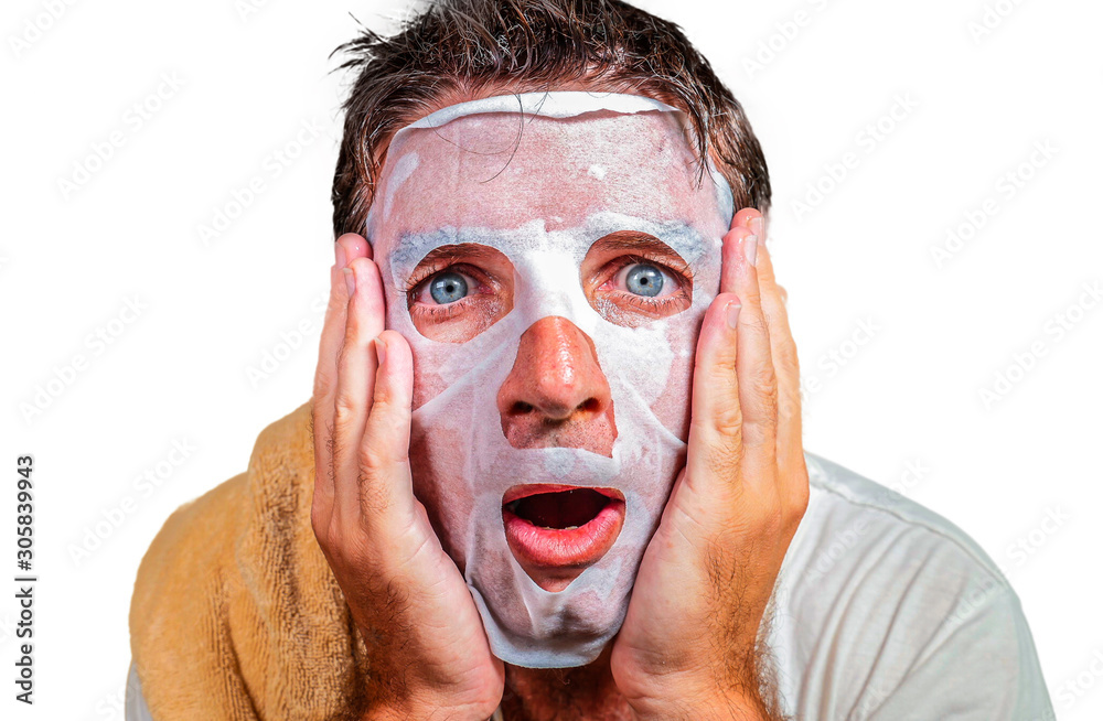 lifestyle isolated background portrait of young weird and funny man at home trying using paper facial mask cleansing applying anti aging beauty treatment lifestyle isolated background portrait of young weird and funny man at home trying using paper facial mask cleansing applying anti aging beauty treatment