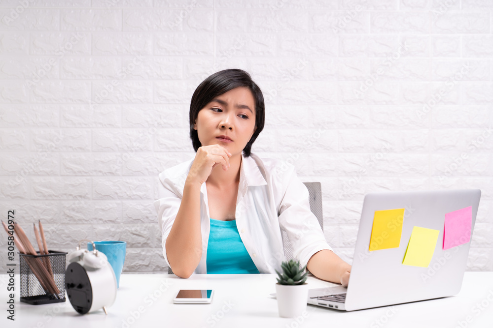 Thoughtful woman sitting at home office working using computer laptop Thoughtful woman sitting at home office working using computer laptop
