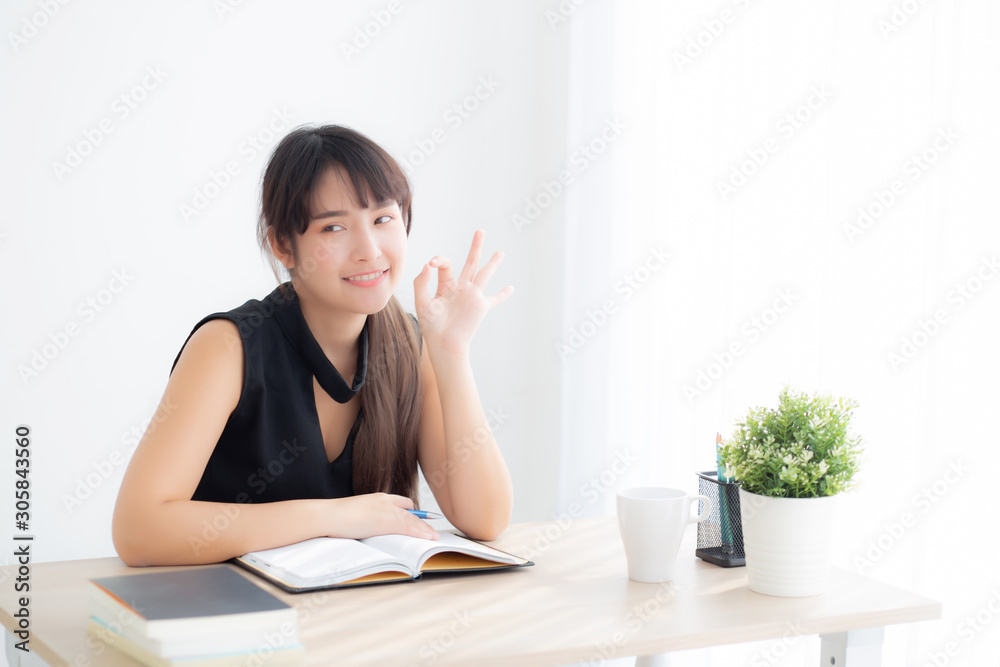 Beautiful portrait young asian woman smiling sitting study and learning writing notebook and diary in the living room at home, girl homework, business woman working on table, education concept. Beautiful portrait young asian woman smiling sitting study and learning writing notebook and diary in the living room at home, girl homework, business woman working on table, education concept.