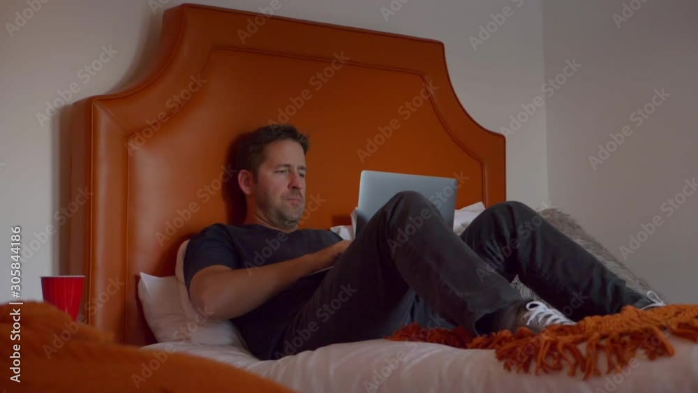 Static shot of male in hotel room, working on laptop alone Static shot of male in hotel room, working on laptop alone