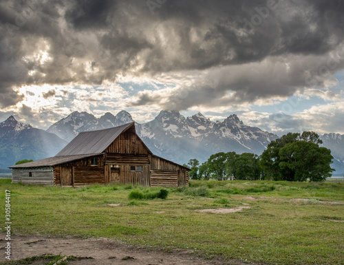Barn at the base of a snow capped mountain range