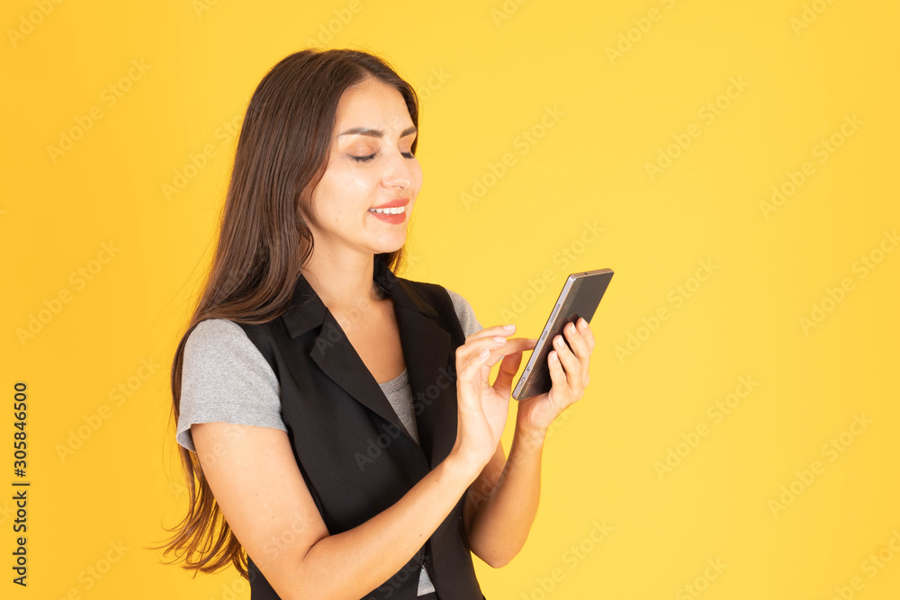 A woman standing and playing with a mobile phone In the yellow background A woman standing and playing with a mobile phone In the yellow background