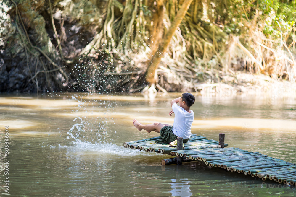 Kid boy sit on the Bamboo bridge beside the lake Kid boy sit on the Bamboo bridge beside the lake