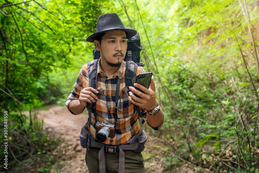 man traveler with backpack using smartphone in the forest