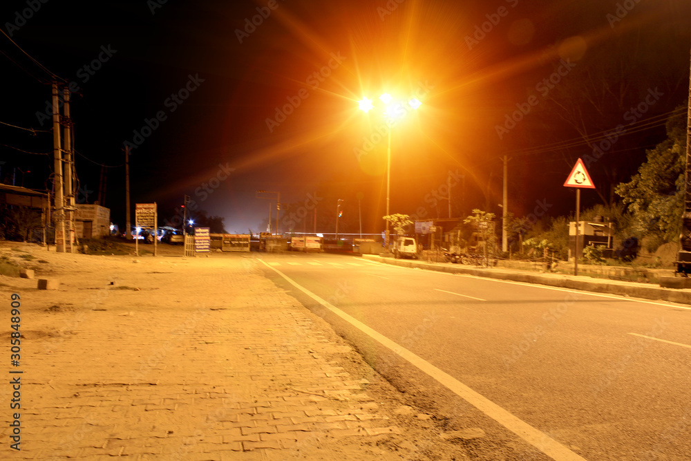 Rohtak, Haryana, India - July 29, 2018: Empty road at night illuminated with street light.