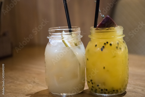 a cocktail of passion fruit and pear. a couple of cans of lemonade are on the table.