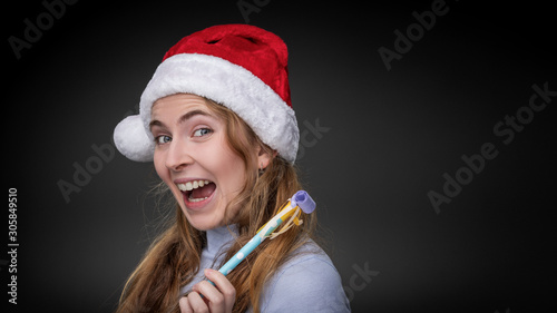 Photos An excited young girl wearing a christmas hat holds a blow tickler