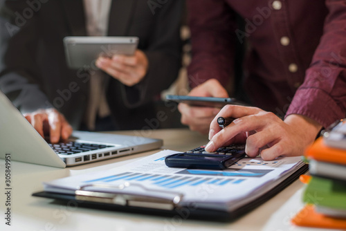 Businessman working as a team start meeting the new marketing project plan By business people using tablets and graph documents Calculate the amount of money for the project.