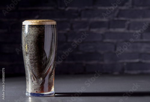 Fotografia A dark Irish dry stout beer glass with a black brick on the background
