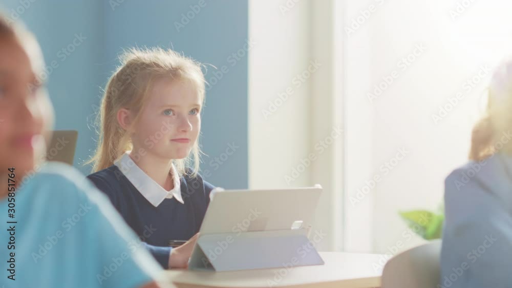 Elementary School Computer Science Class: Cute Girl Uses Digital Tablet Computer, Raises Hand to Ask Question. Children Getting Modern Education in STEM, Playing and Learning. Slow Motion