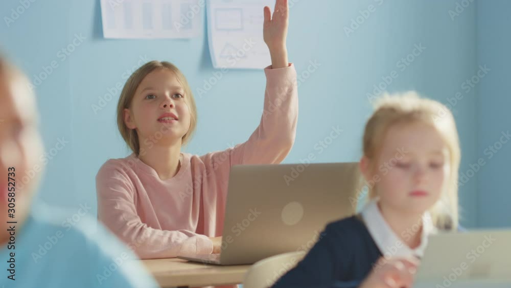 Elementary School Computer Science Class: Cute Girl Uses Digital Tablet Computer, Raises Hand to Answer Question. Children Getting Modern Education in STEM, Playing and Learning. Slow Motion Elementary School Computer Science Class: Cute Girl Uses Digital Tablet Computer, Raises Hand to Answer Question. Children Getting Modern Education in STEM, Playing and Learning. Slow Motion